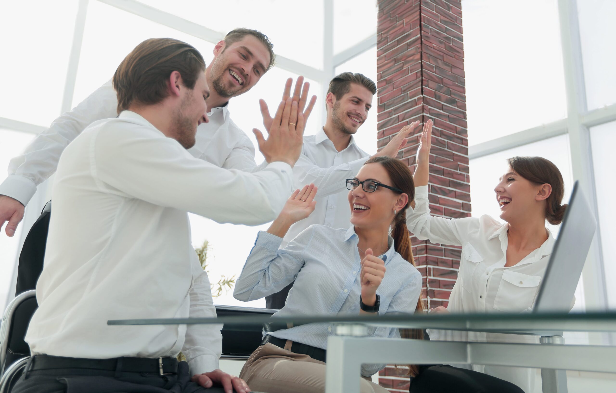 Happy business team giving high-fives in an office, celebrating success with AI chatbot benefits for businesses.