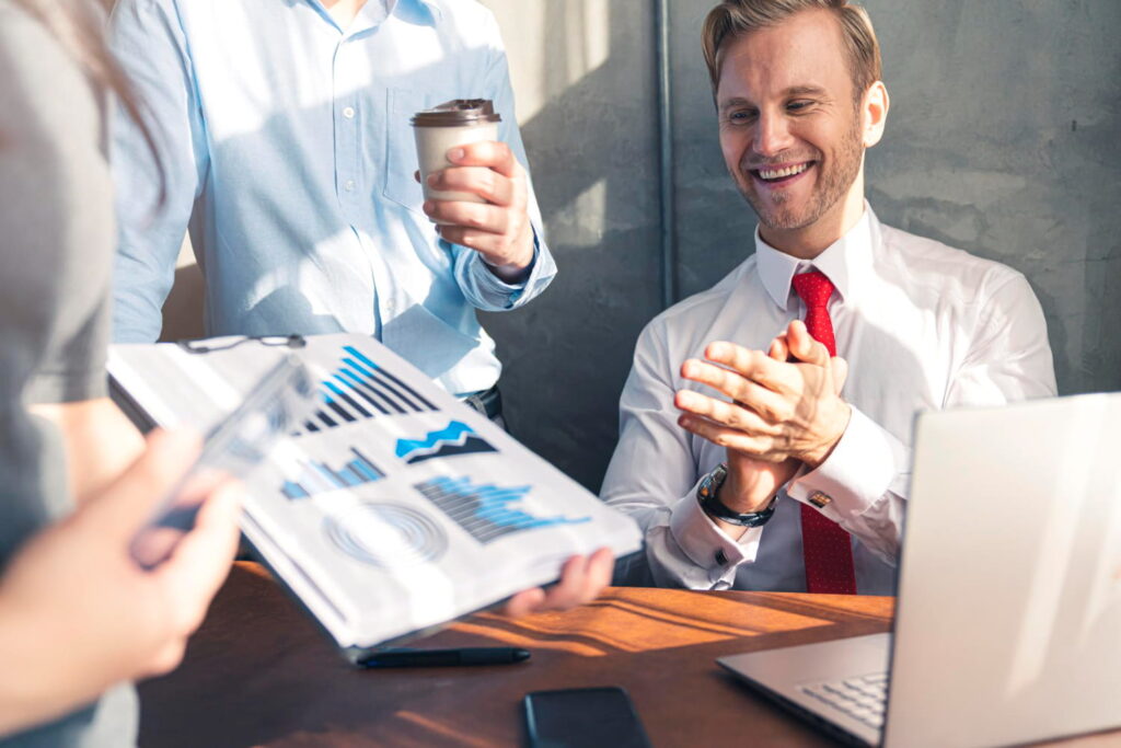 Business professionals reviewing performance reports while discussing a virtual assistant chatbot solution during a team meeting.