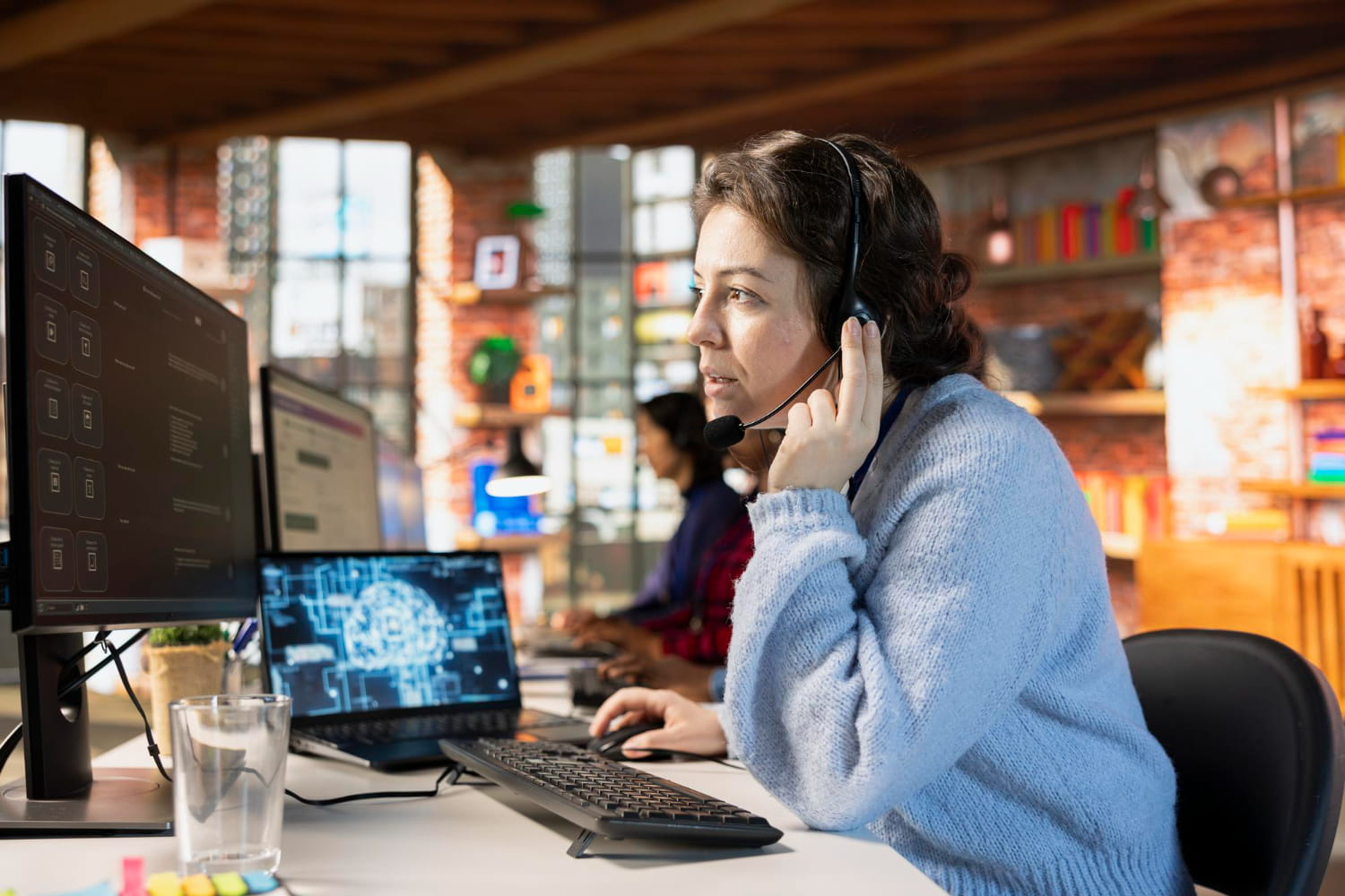 Customer support representative wearing a headset while using AI-powered software to assist customers in a modern office.